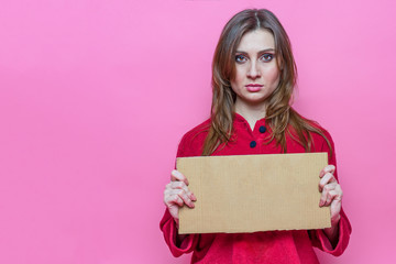 portrait sad beauty young brunette girl with long haire in red pajamas with a cardboard sign in hands. Template.