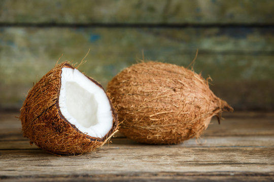 Fresh whole and cut in half coconuts on wooden background