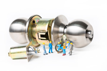 Selective focus of miniature engineer and worker prepare Stainless steel round ball door knob components on white background as Locksmith, business and industrial concept.