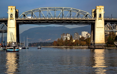 Vancouver Canada, downtown. Burard Street  Bridge, pleasure boat pass under the bridge. Behind the bridge is an autumn city landscape at the background of a mountain ridge.
