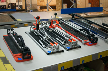 Different tile cutters on store shelves isolated on market background.