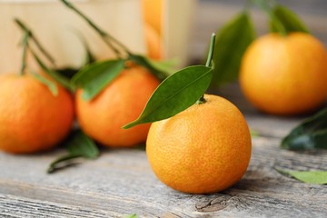 Fresh tasty tangerines with leaves on wooden table 