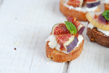 Bruschetta with goat cheese and figs on white wooden table