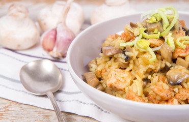 Risotto with mushrooms and chicken decorated with leek on a wooden background