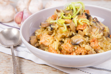 Risotto with mushrooms and chicken decorated with leek on a wooden background