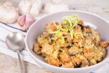 Risotto with mushrooms and chicken decorated with leek on a wooden background