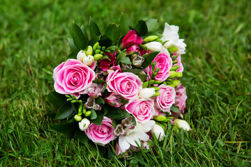 Beautiful bridal bouquet of flowers on green meadow
