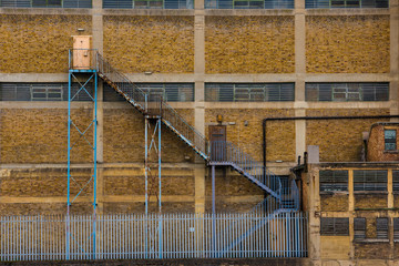 Exterior facade of dilapidated industrial building with fire escape staircase