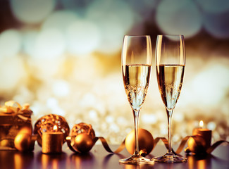 two champagne glasses against holiday lights and fireworks - new year celebration