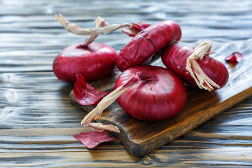 Sweet red onions on an old wooden board.