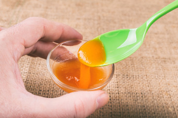 Hand holding a glass of orange jelly made of Psyllium mucilage