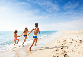 Fototapeta na wymiar Kids running along beach during summer vacation