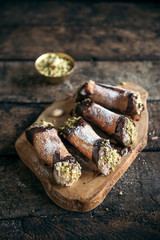 Homemade cannoli with pistachios served on the wooden background,selective focus