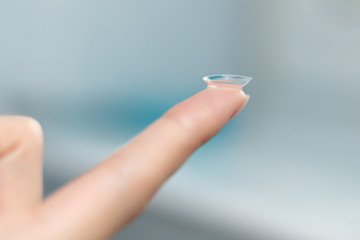 girl holds finger on a contact lens, closeup