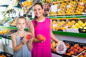 Fototapeta na wymiar mother with girl taking peaches on market .