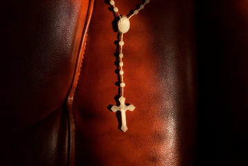 white rosary on a leather red sofa