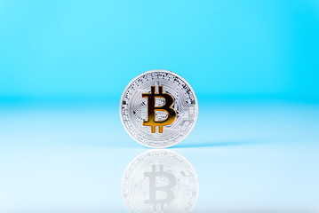 Golden bitcoin isolated on blue background with reflection