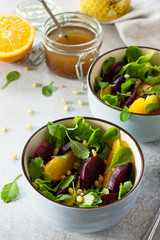 Homemade snacks on a gray stone or slate background. Salad with beets, orange, arugula and pine nuts.