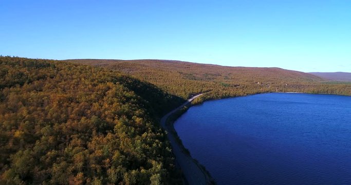 Arctic landscape, Cinema 4k aerial view of a car, on a road between mountains and mantojarvi lake , in autumn colors Lapland, on a sunny autumn day, in Utsjoki, Lappi, Finland