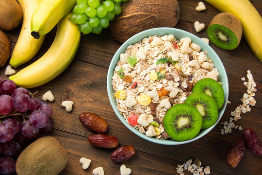 useful breakfast cereal muesli with dried fruits in a plate around exotic fruits
