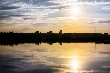 Colorful sunset on the lake with reflections of hills, trees and buildings. Slovakia