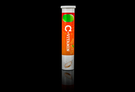 Nutritional supplement. A tube package of vitamin C effervescent tablets isolated on black background.