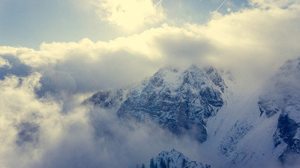 Obraz premium Aerial view of clouds circling around mountain ridge.