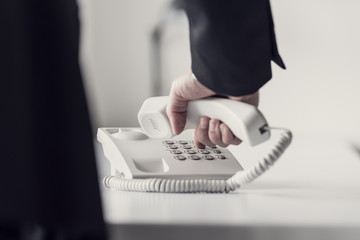 Retro toned image of a businessman dialing telephone number - obrazy, fototapety, plakaty