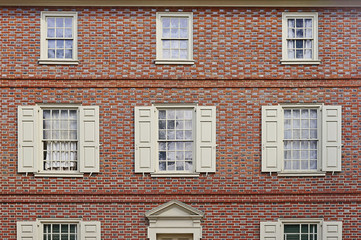 Obraz premium Old red brick wall with white shutters