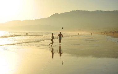 Fototapeta na wymiar Pareja jugando con un balón en la playa de Bolonia, costa de Cádiz, España