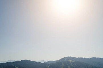 The blue sky and the rays of the sun above the tops of the mountains, free space for your text.