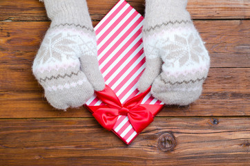 Female hands in mittens unpack the gift on a wooden table.