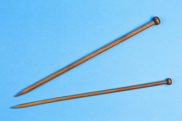 Wooden knitting needles on blue background.