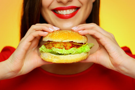 Close up face portrait of smiling woman holding big burger.