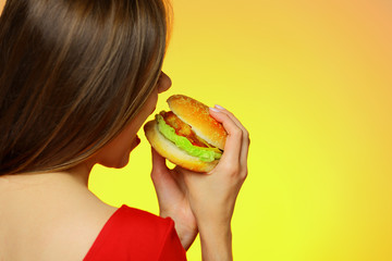 Woman bites burger back close up portrait
