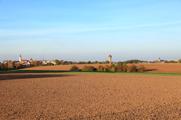 Krajobraz wiejski jesienią, pola i miasteczko na horyzoncie.