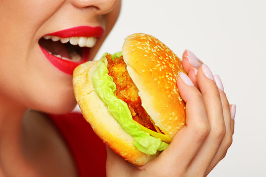 Close up face woman bites burger.