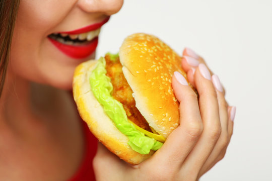 Close up face woman bites burger.