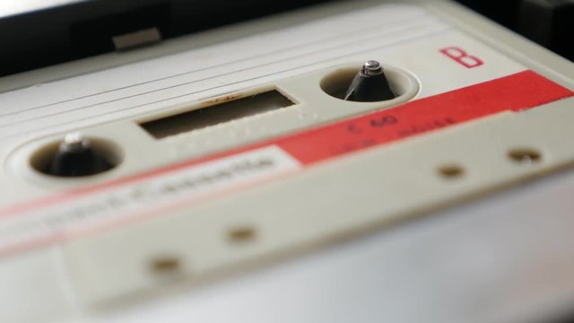 Old music archives on cassette in casettophone close-up footage - Retro audio tape player supply spindle