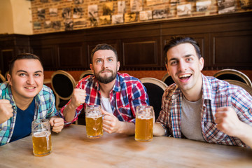 Group of young beautiful friends watching TV and cheering for their team while resting in pub.
