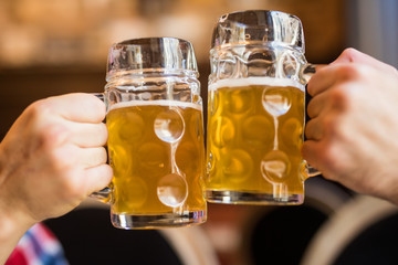 Close-up of people toasts with beer in pub.