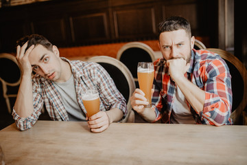 Young bearded man looking upset and sad having beer at the pub copyspace depression stress tired exhausted crisis drinking problems issues unhappy disappointment regret sadness loneliness alcohol