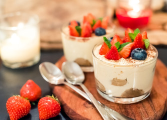 Homemade italian dessert tiramisu with strawberries, mint and blueberry in glass