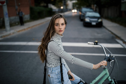 Portrait of young woman cycling on city street