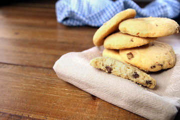 Selection of choc chip and fruit cookies, on a serviette on a wooden table. Copy space for text