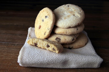 Selection of choc chip and fruit cookies, on a serviette on a wooden table