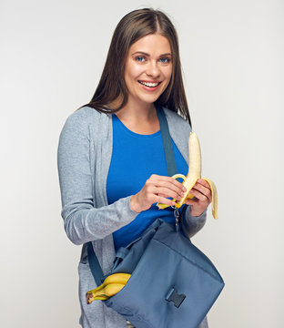 Smiling woman holding food bag eating banana.