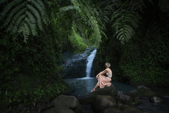 woman sitting in front of waterfall oasis