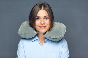 Smiling beautiful woman with travel pillow on neck.