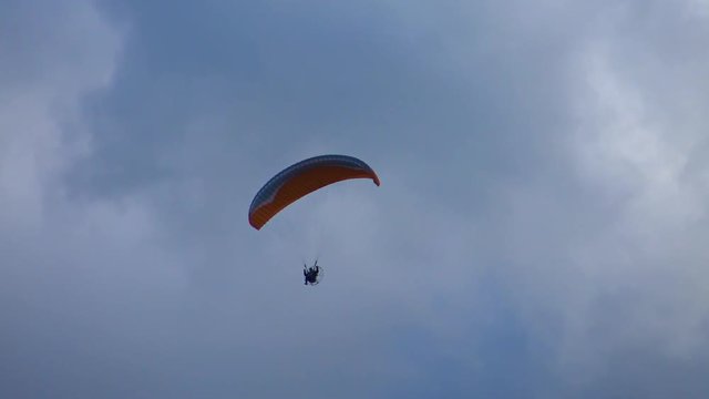 Brave flight of a paraglider high in the storm clouds. Air sport and recreation. A powered paraglider - a glider with a dorsal power plant, providing the rise and moving in the air.  